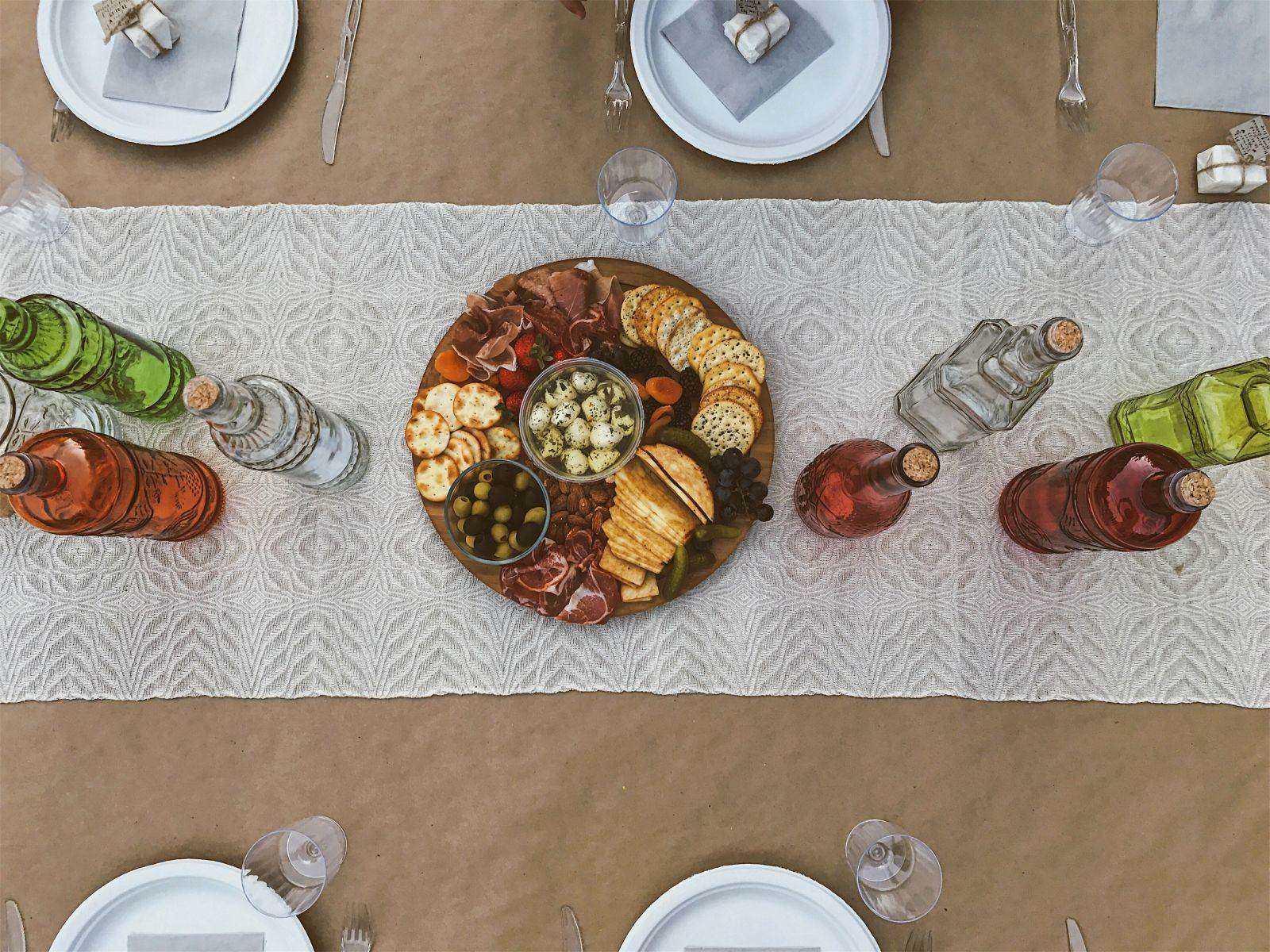 Photo of a white table runner on a table with a tray and bottles on it.