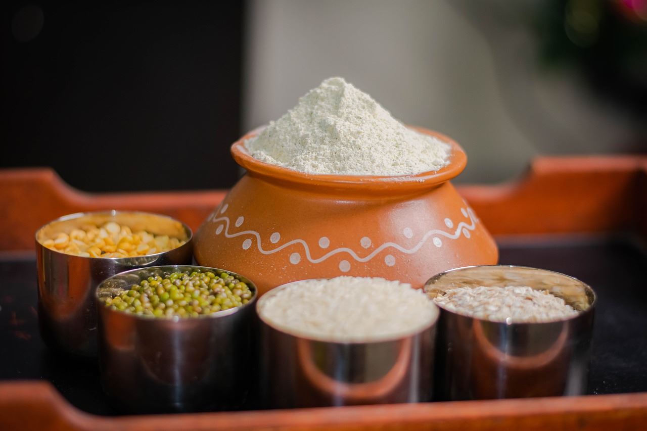 A clay pot and metal jars containing powders and spices.