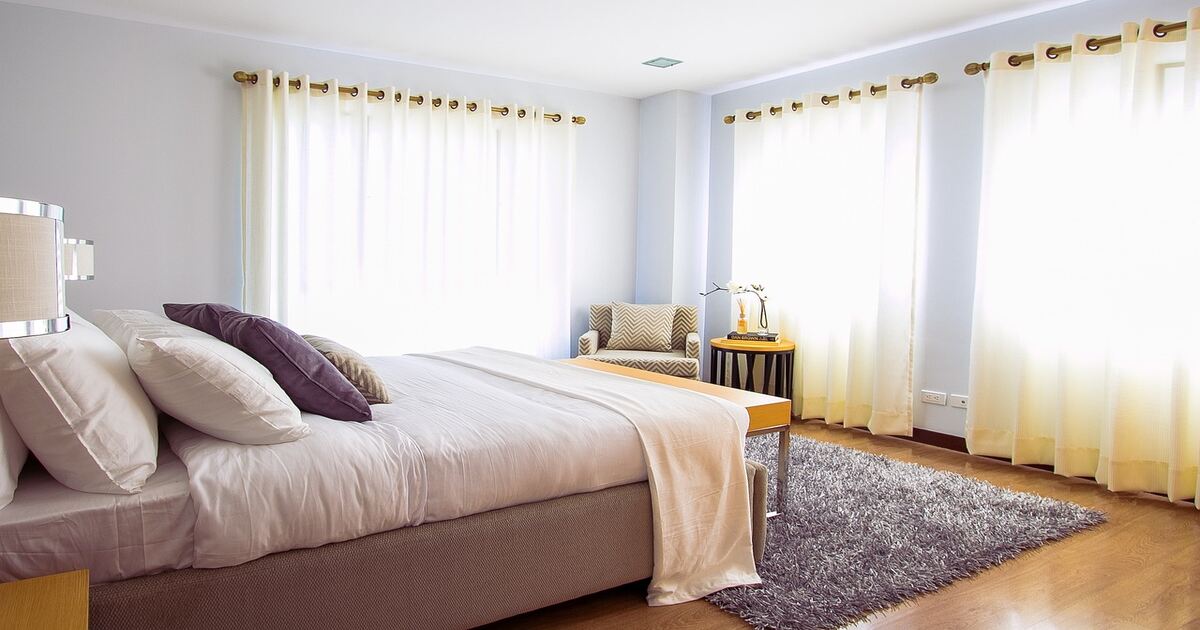 A well-lit bedroom and a bed with cotton bedding.