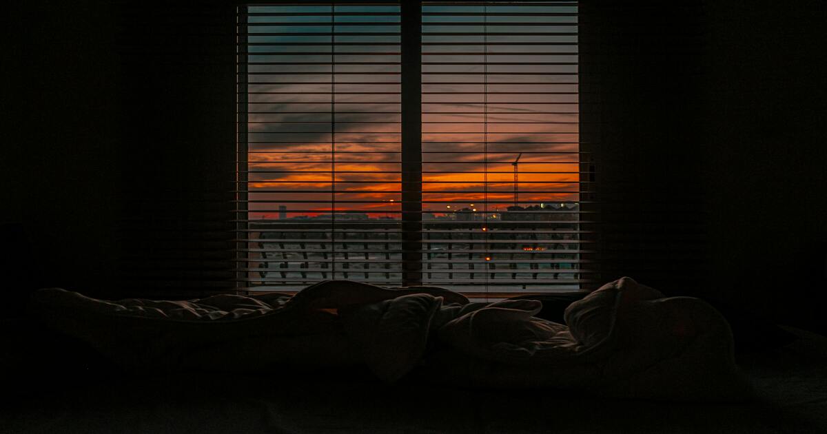 A bedroom with dark bedroom wall colours at sunset.