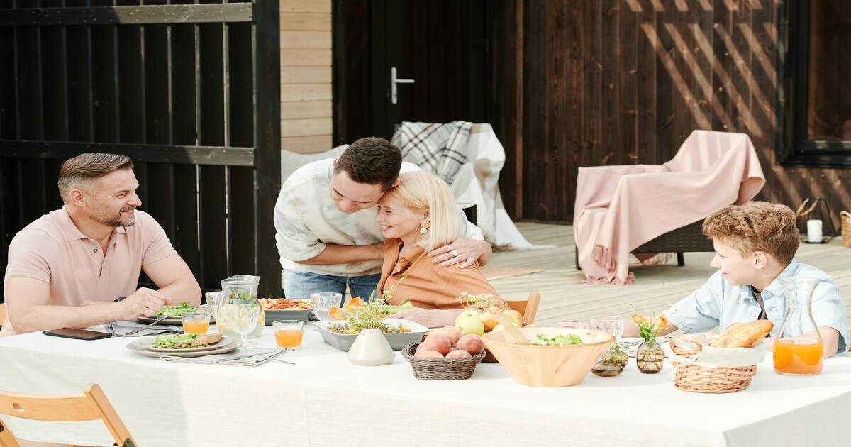 A family sitting at a dining table covered with white table linens.