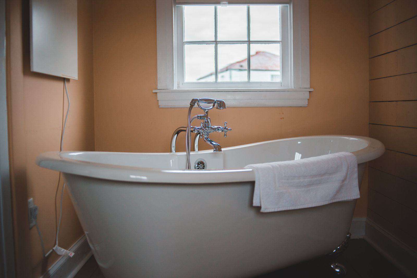 A bathroom with a mirror and ceramic bathtub.