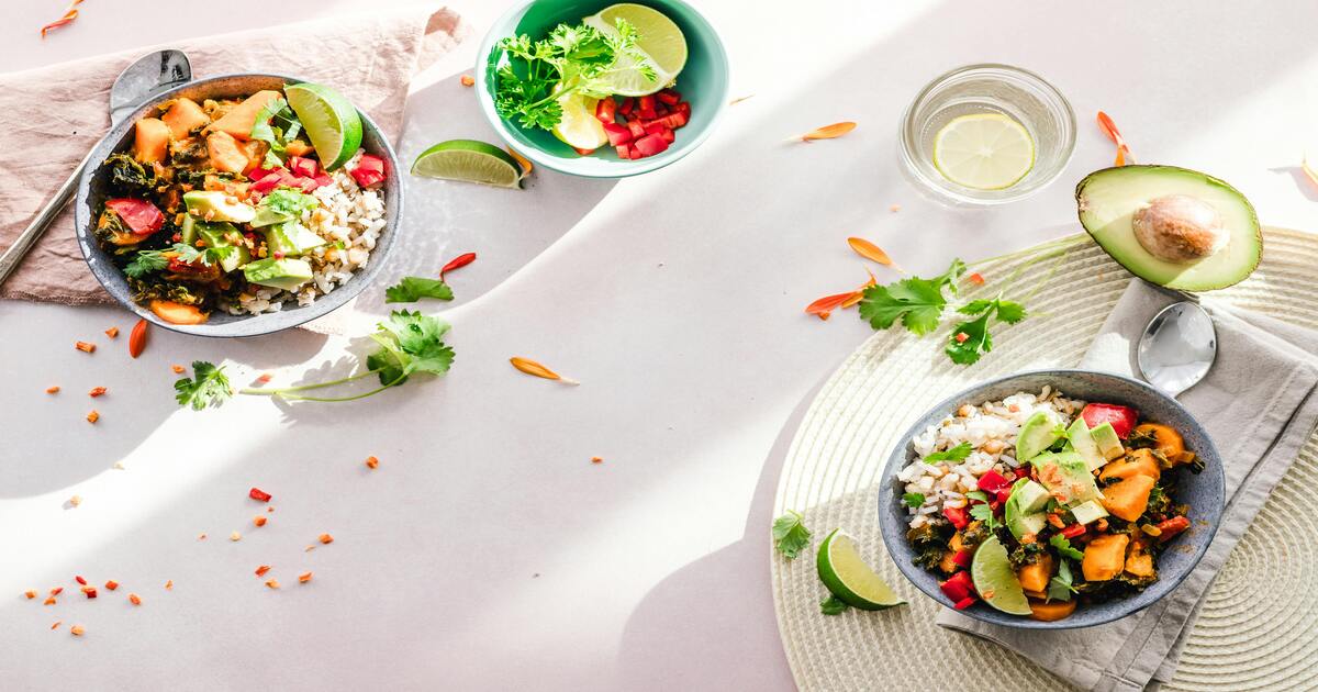 An image of different types of salads in bowls on a white table linen.