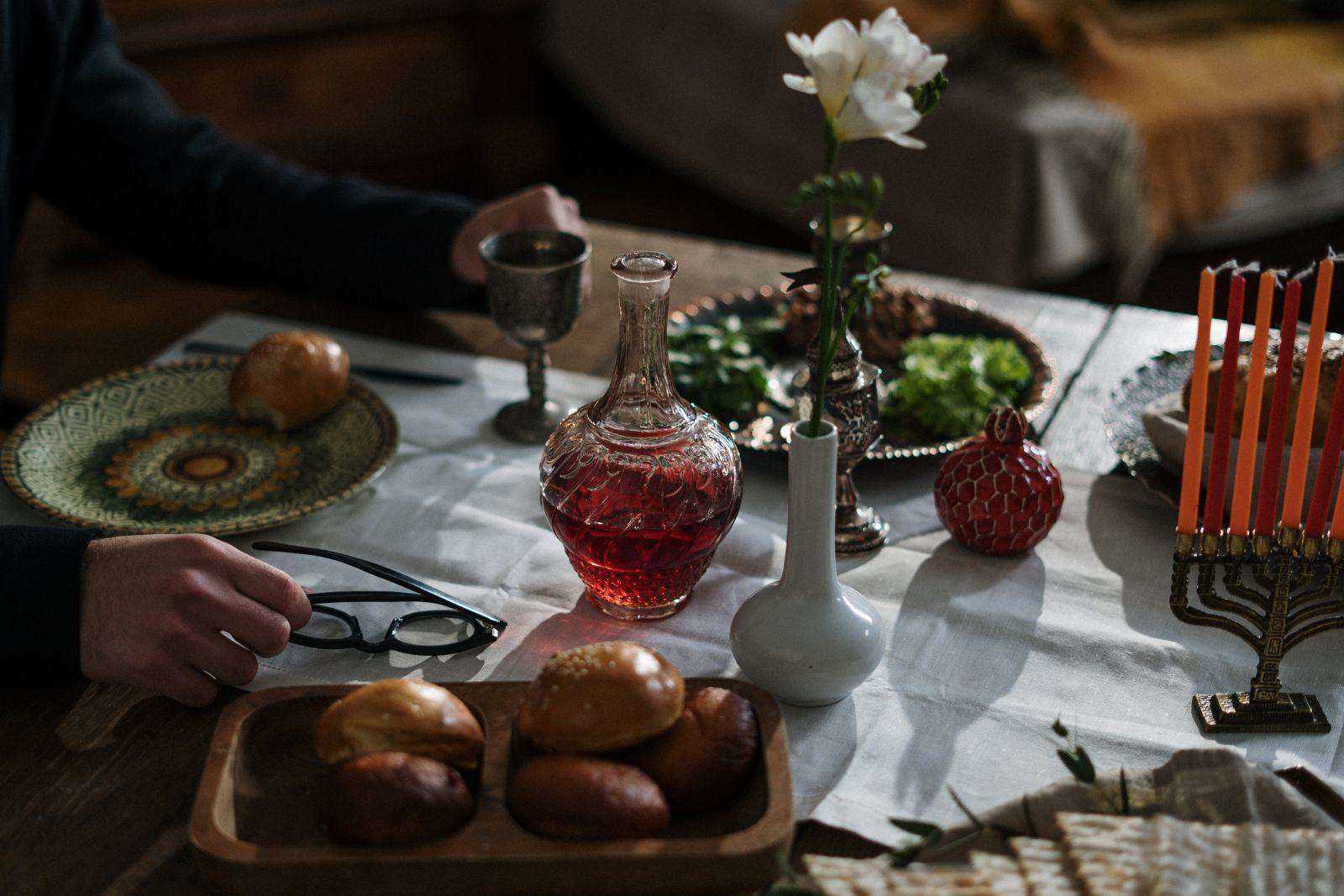 A white flower in a vase on a table set for dining. 